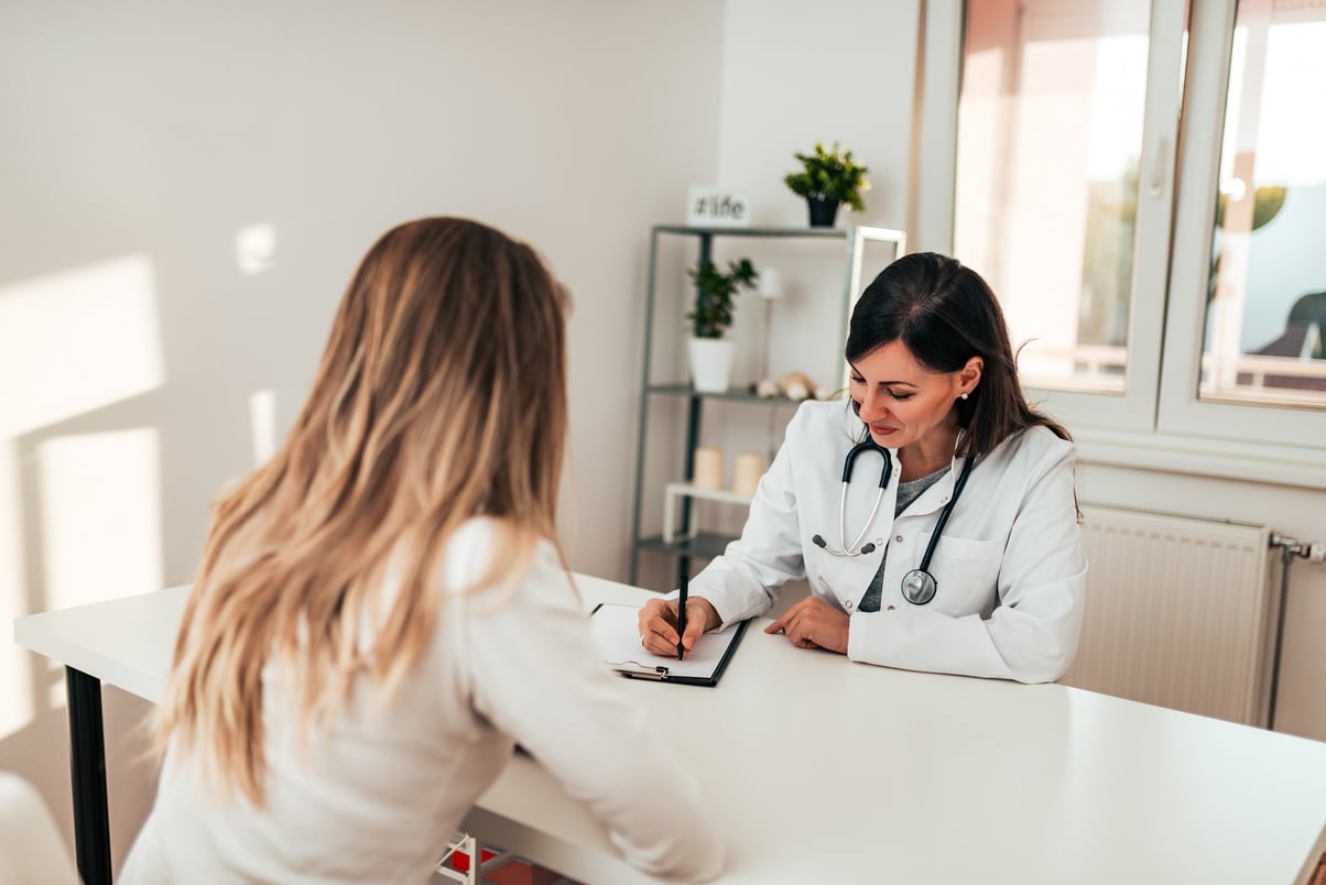 Female doctor writing prescription to her young patient.